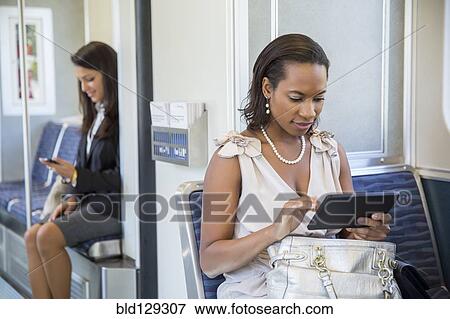Businesswomen using technology on train View Large Photo Image Stock Photo - Businesswomen using technology on train. Fotosearch