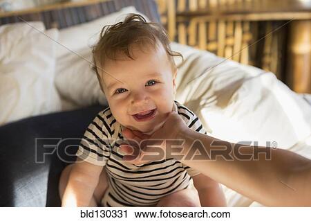 Stock Image - Caucasian baby laughing on bed. Fotosearch