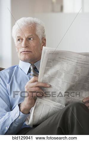 Caucasian businessman reading newspaper in office View Large Photo Image Stock Image - Caucasian businessman reading newspaper in office. Fotosearch