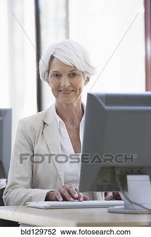 Stock Image - Caucasian businesswoman working at desk. Fotosearch