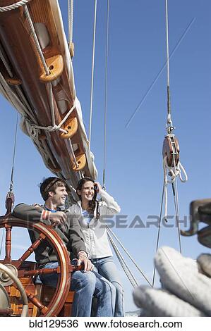 Caucasian couple at helm of sailboat View Large Photo Image Stock Photograph - Caucasian couple at helm of sailboat. Fotosearch