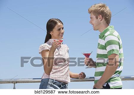 Stock Photo - Caucasian couple enjoying cocktails outdoors. Fotosearch