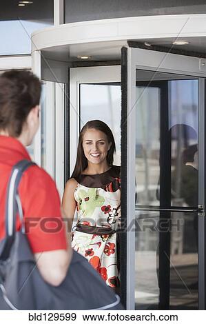 Stock Photo - Caucasian couple greeting at revolving door. Fotosearch