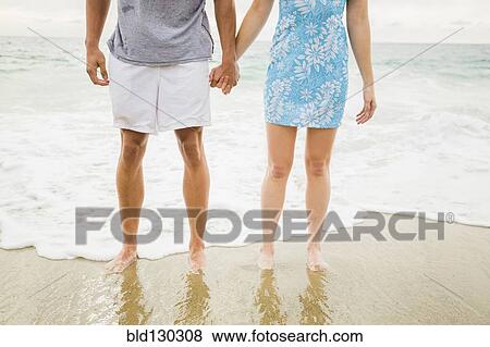 Stock Photo - Caucasian couple holding hands on beach. Fotosearch