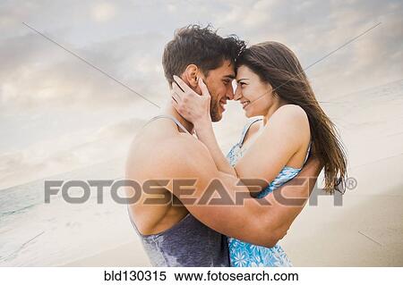 Stock Photography - Caucasian couple hugging on beach. Fotosearch