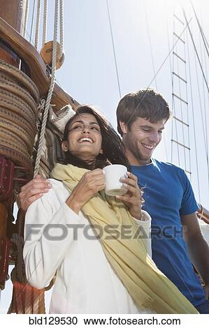 Stock Image - Caucasian couple on sailboat. Fotosearch