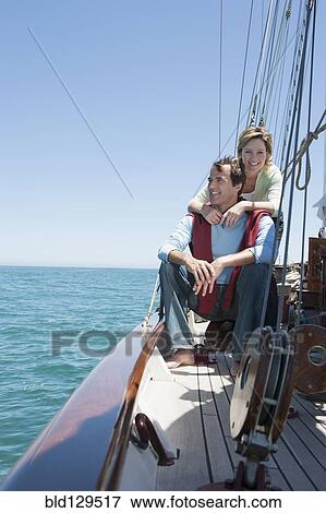Stock Photo - Caucasian couple relaxing on sailboat. Fotosearch