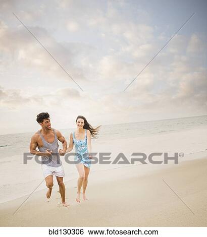 Stock Photograph - Caucasian couple running on beach. Fotosearch
