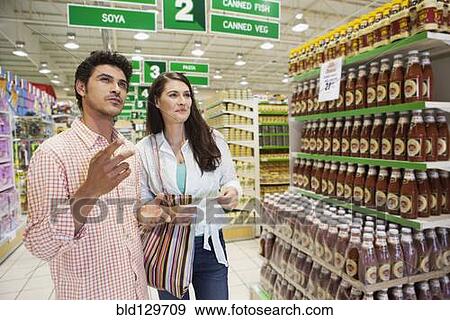 Stock Photo - Caucasian couple shopping in grocery store. Fotosearch