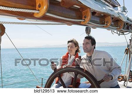 Caucasian couple steering sailboat View Large Photo Image Stock Image - Caucasian couple steering sailboat. Fotosearch