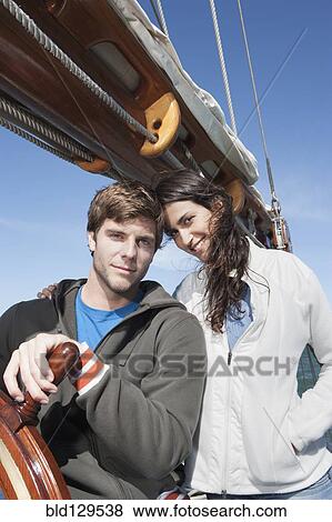 Stock Photo - Caucasian couple steering sailboat. Fotosearch