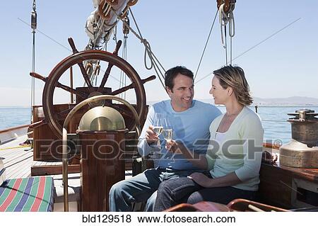 Caucasian couple toasting each other on sailboat View Large Photo Image Stock Photo - Caucasian couple toasting each other on sailboat. Fotosearch