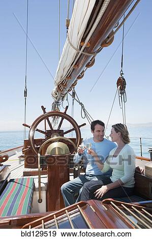 Stock Photo - Caucasian couple toasting each other on sailboat. Fotosearch