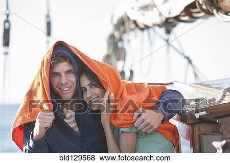 Stock Photo - Caucasian couple under blanket on sailboat. Fotosearch