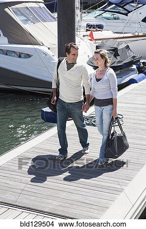 Picture - Caucasian couple walking on dock. Fotosearch
