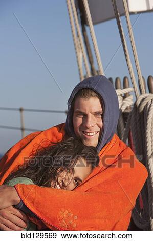 Stock Photo - Caucasian couple wrapped in blanket on sailboat. Fotosearch