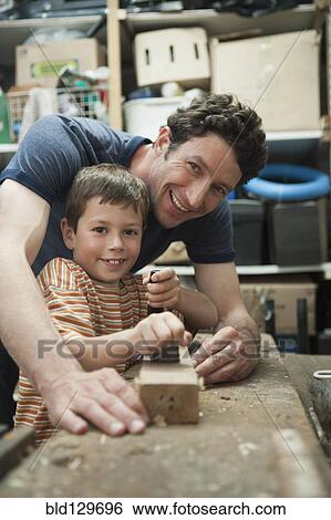 Stock Photograph - Caucasian father and son working in woodshop. Fotosearch