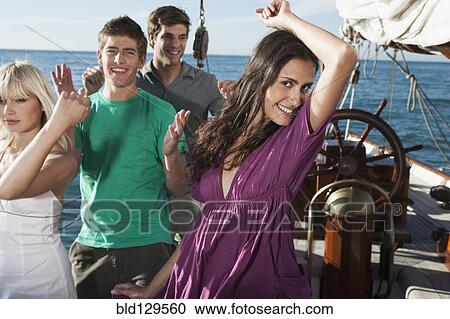 Stock Image - Caucasian friends dancing on sailboat. Fotosearch