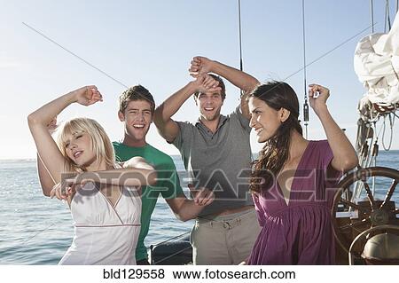 Stock Photo - Caucasian friends dancing on sailboat. Fotosearch