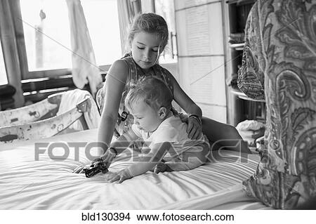 Caucasian girl and baby boy playing on bed View Large Photo Image Picture - Caucasian girl and baby boy playing on bed. Fotosearch