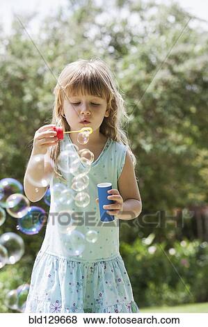 Stock Photo - Caucasian girl blowing bubbles outdoors. Fotosearch