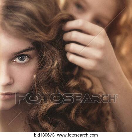 Stock Image - Caucasian girl braiding friend's hair. Fotosearch