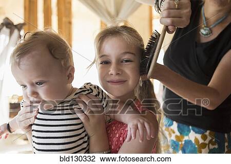 Caucasian girl holding brother as mother brushes her hair View Large Photo Image Stock Image - Caucasian girl holding brother as mother brushes her hair. Fotosearch