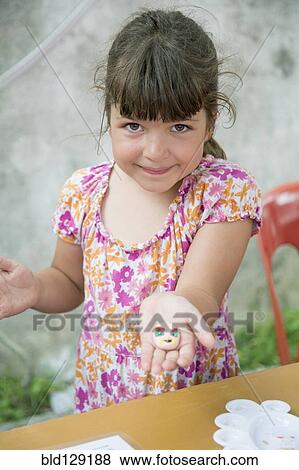 Caucasian girl holding painted rock View Large Photo Image Stock Photo - Caucasian girl holding painted rock. Fotosearch