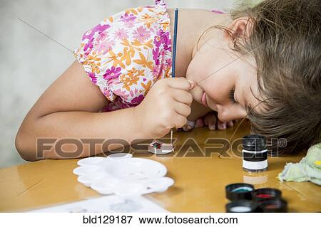 Stock Photo - Caucasian girl painting rock on desk. Fotosearch