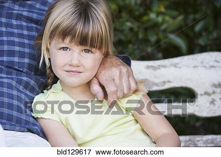 Stock Photo - Caucasian girl sitting with grandfather on bench. Fotosearch