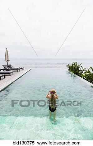 Stock Photography - Caucasian girl swimming in infinity pool. Fotosearch