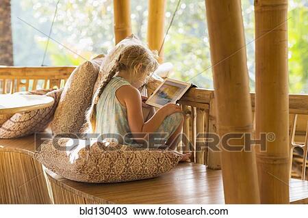 Stock Image - Caucasian girl using digital tablet on patio. Fotosearch