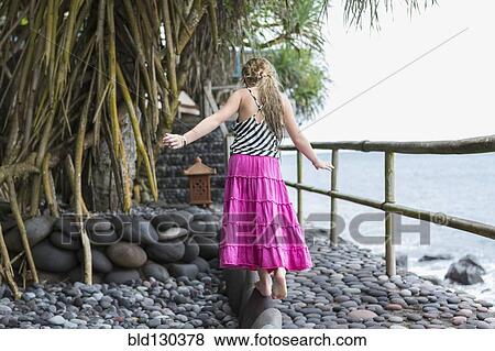 Stock Photo - Caucasian girl walking along stone ledge. Fotosearch