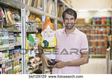 Caucasian man carrying garden gnome in hardware store View Large Photo Image Stock Photo - Caucasian man carrying garden gnome in hardware store. Fotosearch