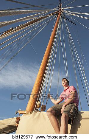 Stock Photo - Caucasian man relaxing on sailboat. Fotosearch