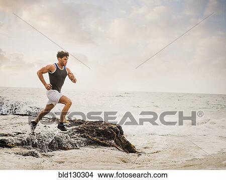 Picture - Caucasian man running on beach. Fotosearch