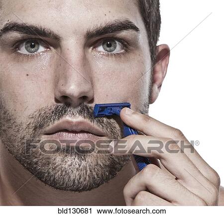 Stock Image - Caucasian man shaving his beard. Fotosearch