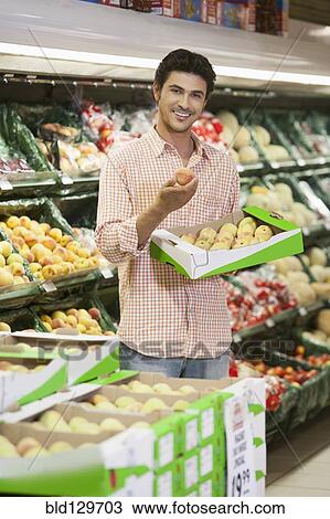 Stock Image - Caucasian man shopping in grocery store. Fotosearch