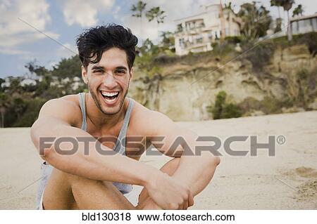Stock Photo - Caucasian man sitting on beach. Fotosearch