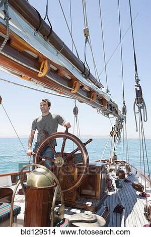 Caucasian man steering sailboat View Large Photo Image Picture - Caucasian man steering sailboat. Fotosearch