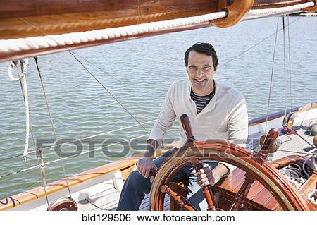 Stock Photograph - Caucasian man steering sailboat. Fotosearch