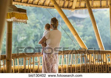 Stock Image - Caucasian mother and baby overlooking view from balcony. Fotosearch