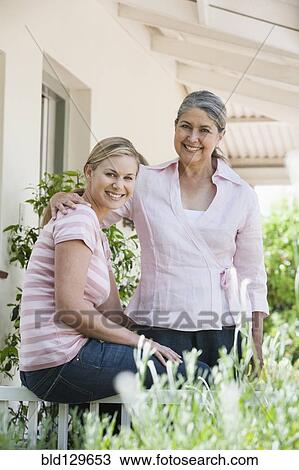 Stock Image - Caucasian mother and daughter smiling on patio. Fotosearch