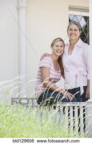 Stock Photograph - Caucasian mother and daughter smiling on porch. Fotosearch