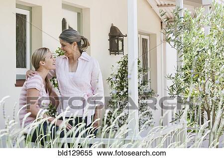 Stock Photography - Caucasian mother and daughter talking on porch. Fotosearch