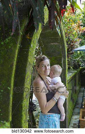Stock Image - Caucasian mother holding baby boy in stone archway. Fotosearch