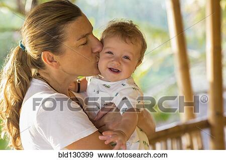 Caucasian mother kissing baby's cheek View Large Photo Image Stock Photo - Caucasian mother kissing baby's cheek. Fotosearch