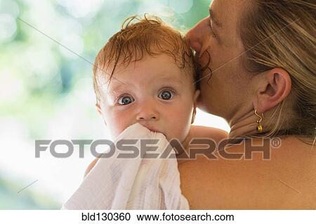 Stock Image - Caucasian mother kissing baby's head. Fotosearch