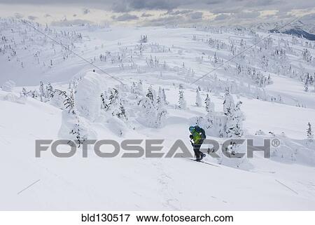 Stock Photo - Caucasian snowshoer walking up snowy hillside. Fotosearch