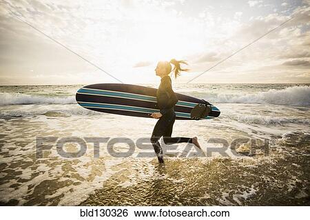 Caucasian surfer carrying board in waves View Large Photo Image Stock Photograph - Caucasian surfer carrying board in waves. Fotosearch